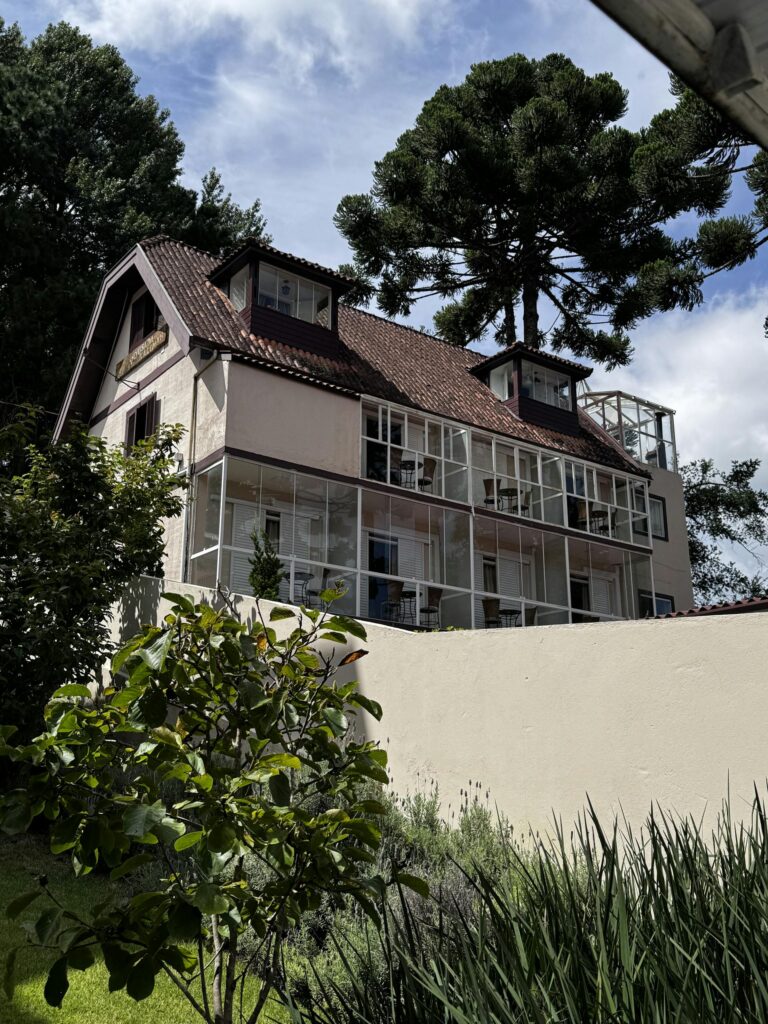 Quaint European-style house with glass windows set in a lush garden under a blue sky.